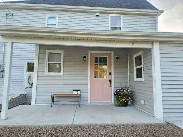 The covered front porch with its pink front door, bench and flower pot